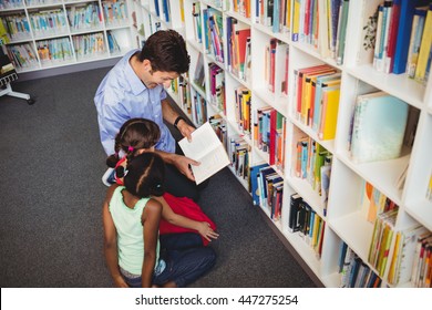 Man Reading A Book For Two Kids In A Library