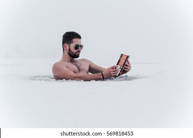  man reading a book in the water ice of the lake