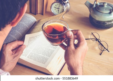 A Man Reading Books And Drinking Tea