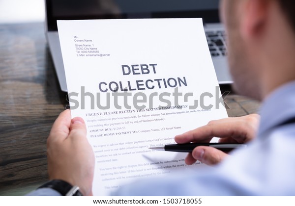 Man Reading\
Debt Collection Notice Letter At\
Desk