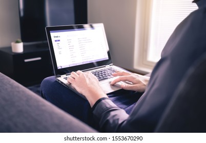 Man Reading Email And Using Laptop In Home Living Room. Checking Received Electronic Web Mail And Replying To Messages. Mockup Inbox On Computer Screen. Business Lifestyle And Entrepreneurship.