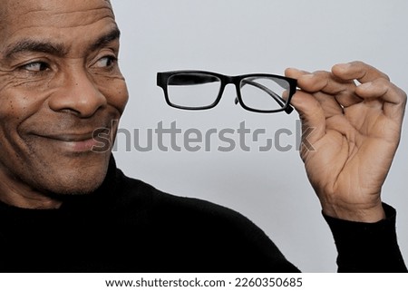 man with reading glasses in his hand on grey background with people stock photo 