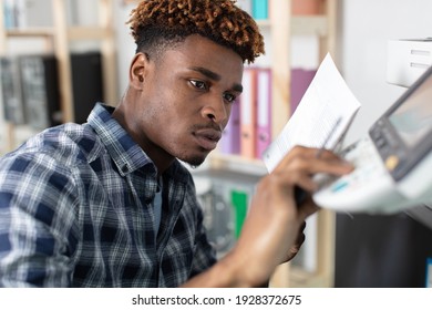 Man Reading Instructions To Repair Photocopier