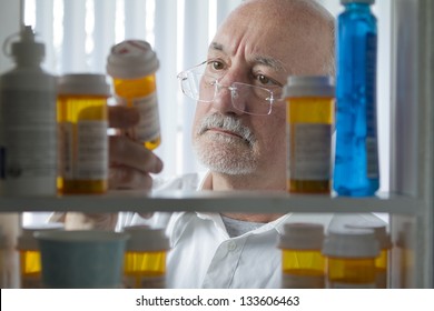 Man Reading Label On Prescription Bottle