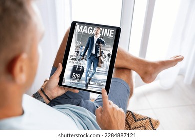 Man reading magazine on tablet computer - Shutterstock ID 2284887121