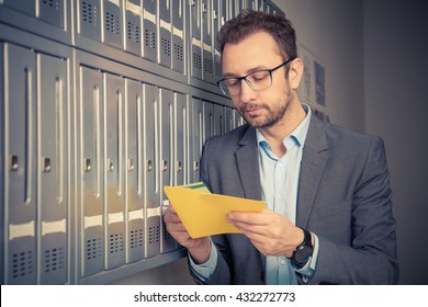 Man Reading Mail And Standing Next To The Letterboxes 