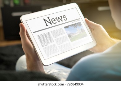 Man reading the news on tablet at home. Imaginary online and mobile news website, application or portal on modern touch screen display. Holding smart device in hand. - Shutterstock ID 726843034