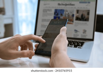 Man reading news online on a smartphone and laptop. Reads articles, newspaper, information concept - Powered by Shutterstock