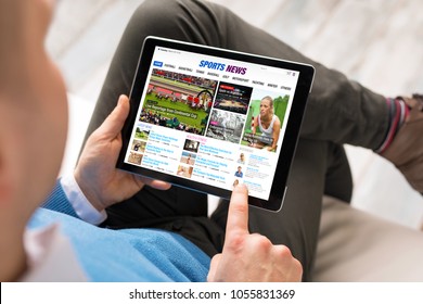 Man reading sports news on tablet. All contents are made up.