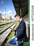 man reading a tablet or ebook in a train station while is waiting for public transport