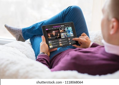 Man Reading Tech News On Tablet While Sitting At Home