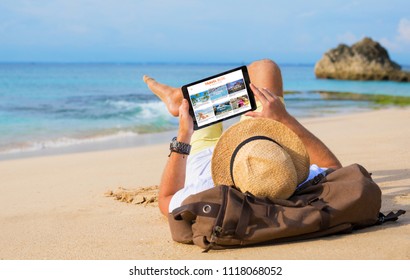 Man Reading Travel Blog On Beach