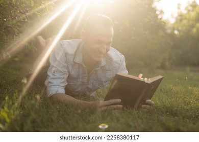 a man reads the Bible on the grass at a park - Shutterstock ID 2258380117