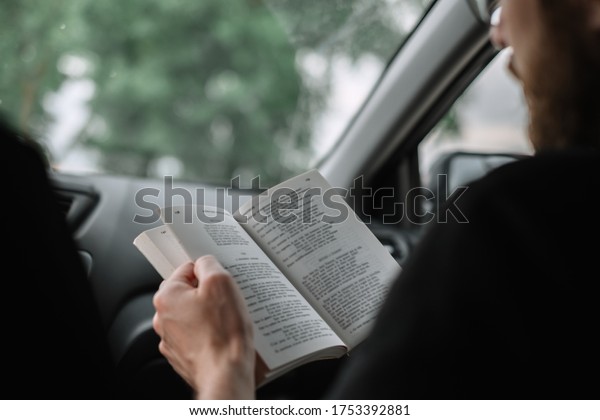 A man reads\
a book in a car during a long\
trip.