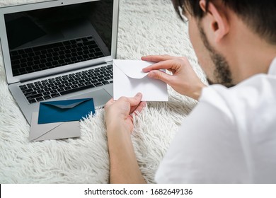 A Man Reads Letters While Lying On A Bed At A Laptop. Man Sends A Birthday Card