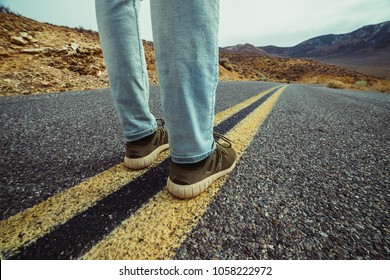 Man ready to take a new way and make a step to new life concept. Feet on empty and free asphalt road in desert.