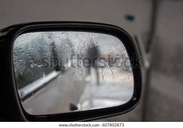Man in rearview mirror on\
rainy day