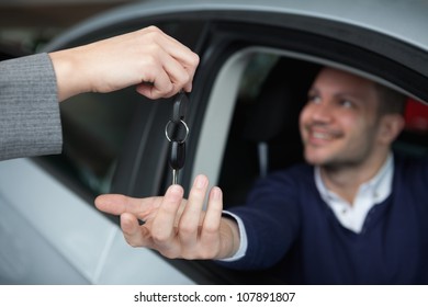 Man receiving car keys while sitting in his car in a garage