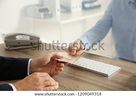 Man receiving money from teller at cash department window, closeup