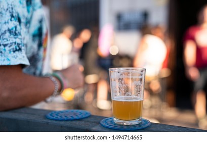 Man Reclined In A Bar With A Half Empty Glass Of Beer In An Outside Party