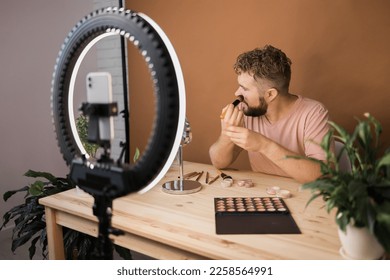 Man recording video vlog while applying cosmetics or explore cosmetic product. Guy making tutorial make-up for his blog on cosmetics.
