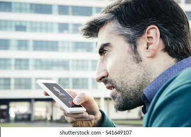 Man Recording Voice Message With Smartphone. All Screen Graphics Are Made Up.