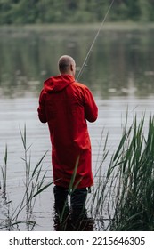 Man In Red Coat Fishing In Lake.