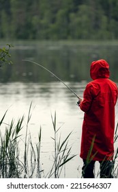 Man In Red Coat Fishing In Lake.