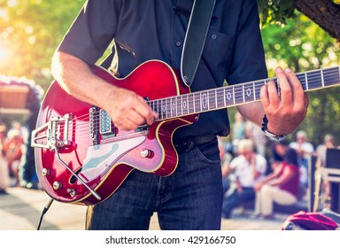 Man With A Red Electric Guitar In The Park Playing A Concert