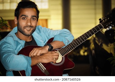 A Man With Red Guitar Watching Camera And Keeping A Beautiful Smile