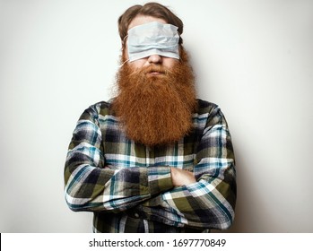 A Man With A Red Hair And A Red Beard Wearing A Face Mask Over His Eyes.  A Bearded Man With A Protective Mask Worn In A Funny Way. Go Crazy In The Quarantine .