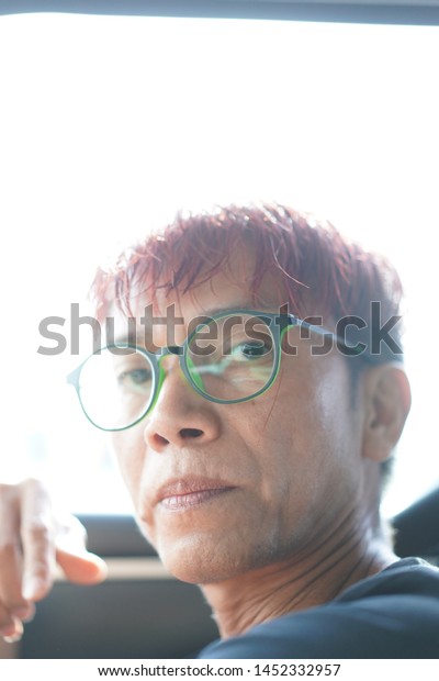 The man with red
hair wear glasses looking hopefully past the camera,The eye of man
in Asia and Glasses accessories personality to look good for all
ages.in-Thailand.