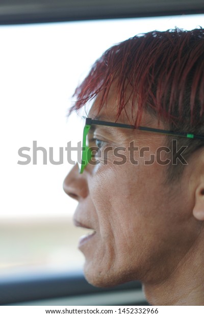 The man with red\
hair wear glasses looking hopefully past the camera,The eye of man\
in Asia and Glasses accessories personality to look good for all\
ages.in-Thailand.