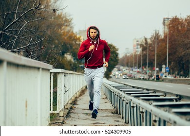 Man in red hoodie jogging beside the road in the city - Powered by Shutterstock