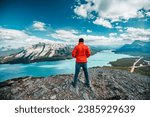 A man with red jacket  enjoying the view from a mountain peak at Alberta, Canada