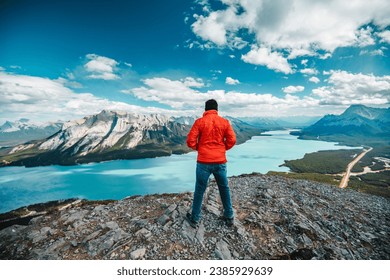 A man with red jacket  enjoying the view from a mountain peak at Alberta, Canada - Powered by Shutterstock