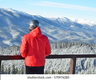 Man in red jacket looking at winter mountains, back view of man with copy space 