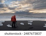 man in red jacket photographed ice blocks on diamond beach