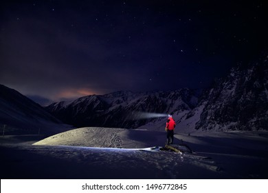 Man In Red Jacket With Ray From His Head Light At Starry Night The Mountain In Ski Resort At Winter