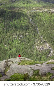 Man in Red Jacket Sitting Alone in Mountains, Vertical Shot