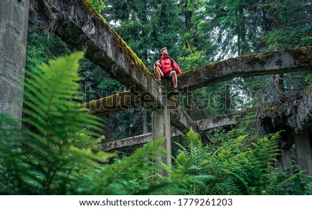 The man with red jacket stands on ruins of old concrete constructions of former tin mine Rolava and prison camp Sauersack near Prebuz, Krusne Hory, Czech Republic