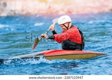 Man in red kayak sails mountain river. Whitewater kayaking, extreme sport rafting.