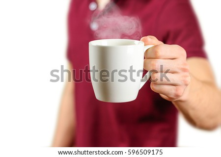 The man in the red shirt shows a clean white Cup. Cup for your design. Empty mug. Isolated on white background.