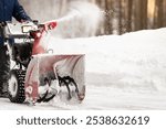 A man with a red snowplow clears the territory from snow. Clearing the territory from snowfall. Selective focus