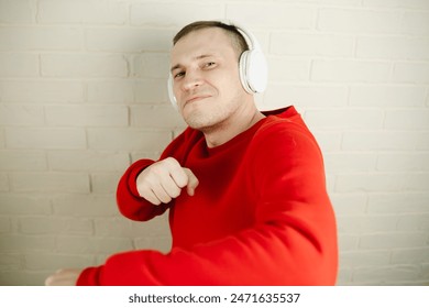 Man In Red Sweatshirt Dances While Listening To Music With Headphones.