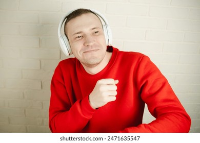 Man In Red Sweatshirt Dances While Listening To Music With Headphones.