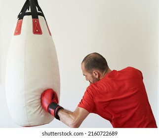 Man In Red T-shirt Hitting Uppercut To Heavy Bag In Boxing Workout