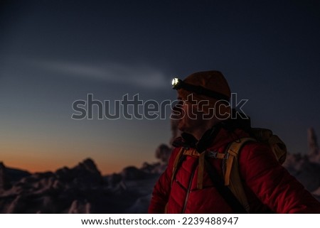 Man in red winter jacket at the way to mountain top at winter.