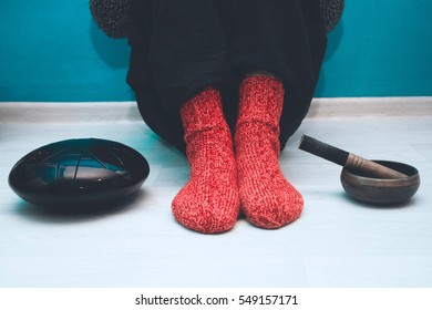 Man in a red woolen socks sitting on the floor in the yoga studio with a singing bowl and steel tongue drum - Shutterstock ID 549157171