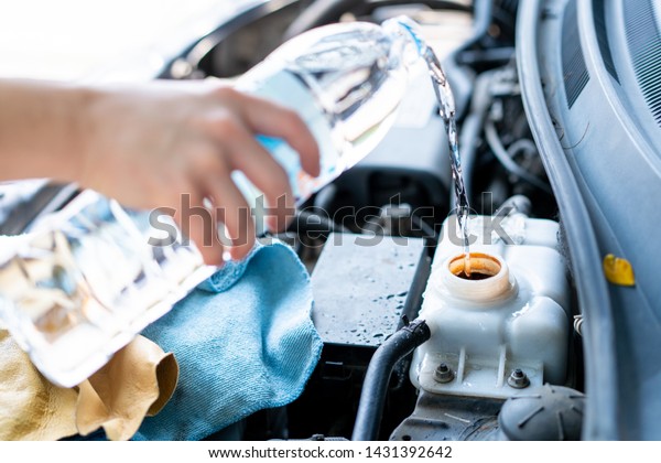 Man\
refill water into car\'s cooler system tank close\
up.